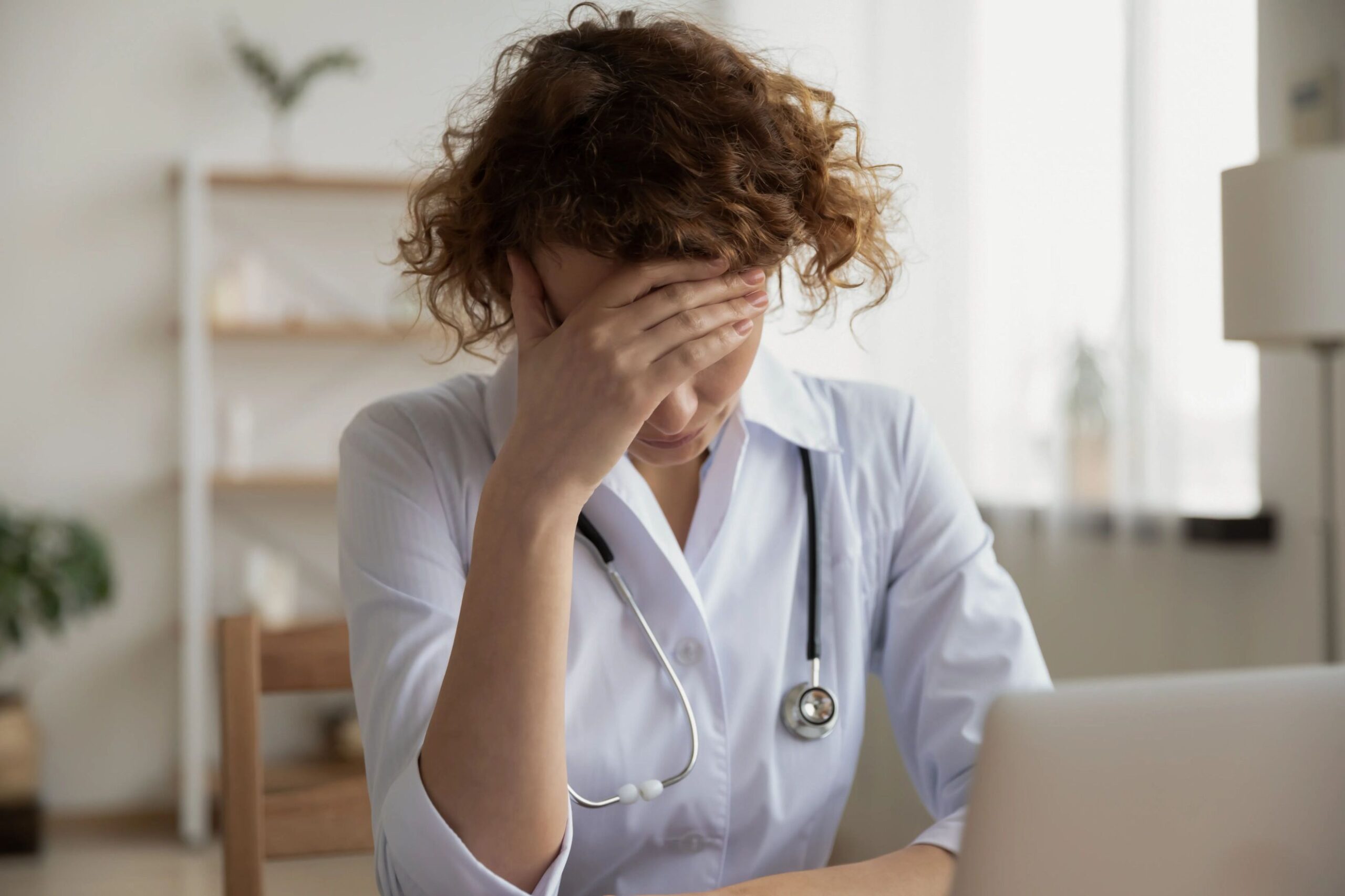 A concerned doctor with her hands on her head.