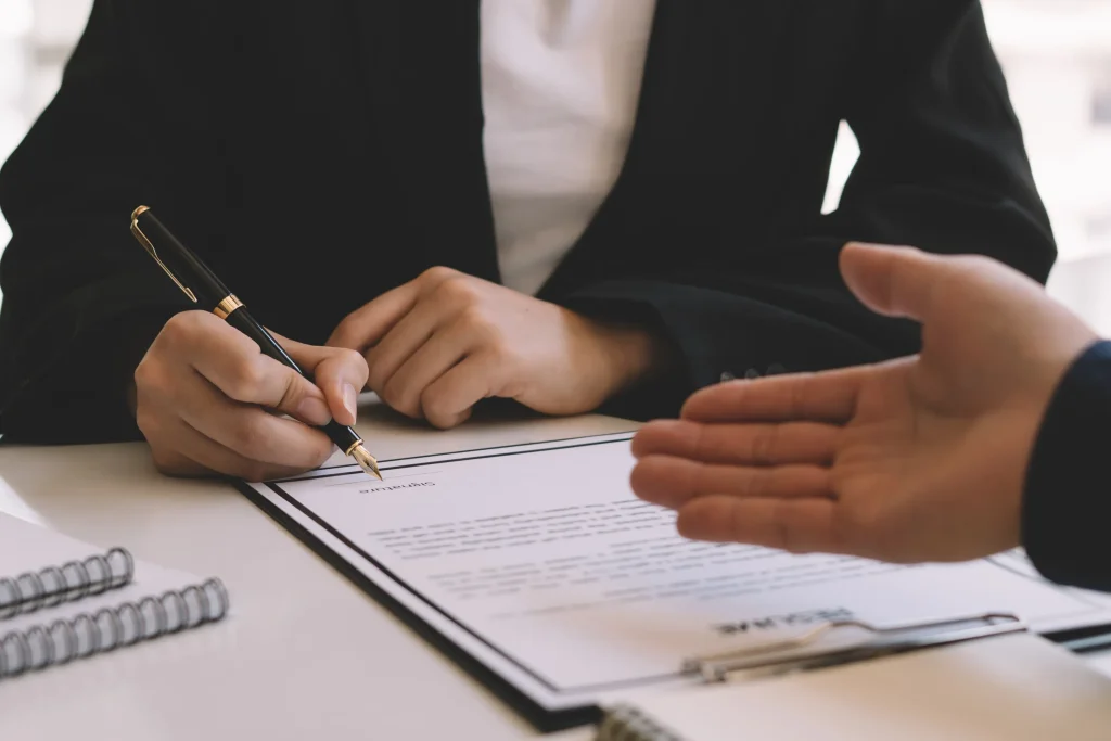 Someone signing a contract in an office.
